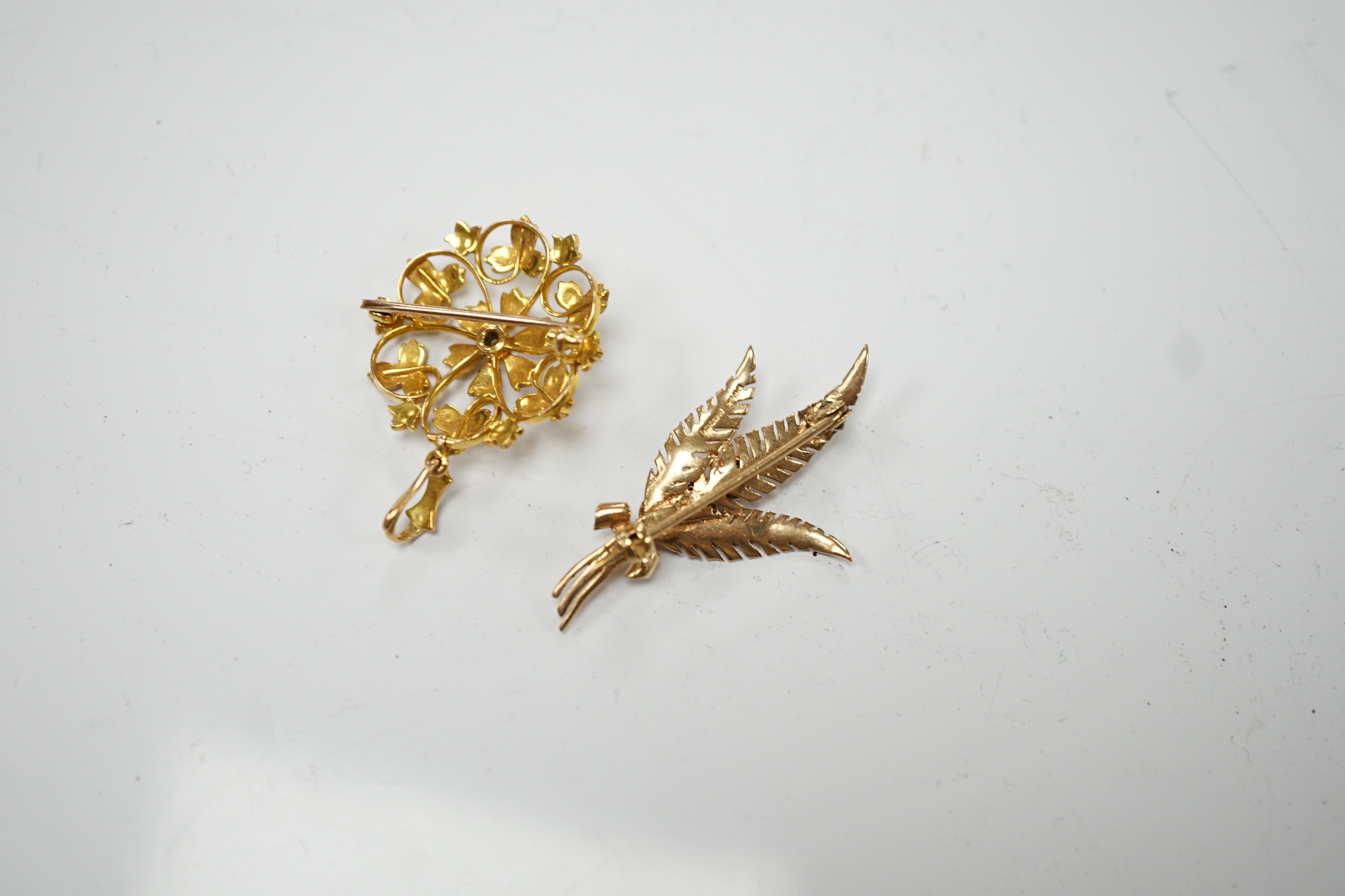An Edwardian yellow metal and seed pearl set circular cluster pendant brooch, 27mm, gross weight 6.2 grams, together with a later 9ct gold, garnet and cultured pearl set foliate brooch, gross weight 4.1 grams.